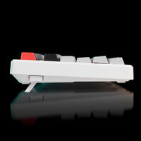 White keyboard with red and black keys on a reflective black surface